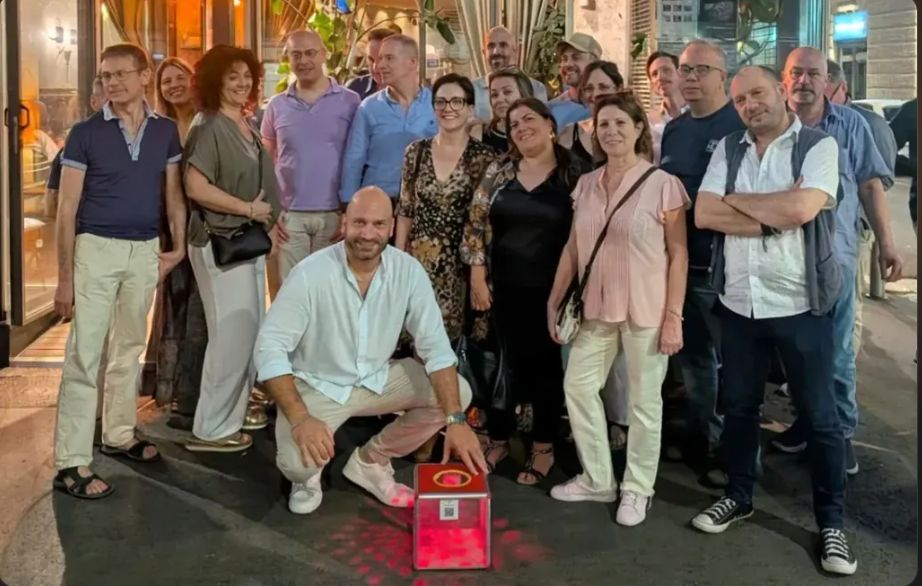 Gruppo di partecipanti davanti a un locale con la box Social Box rossa illuminata